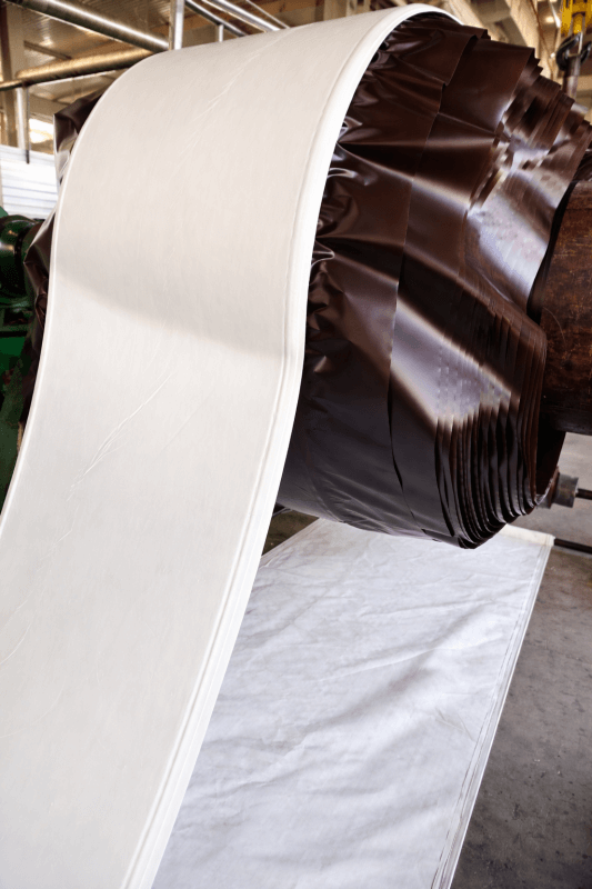 White conveyor belt molding process on industrial drum in factory