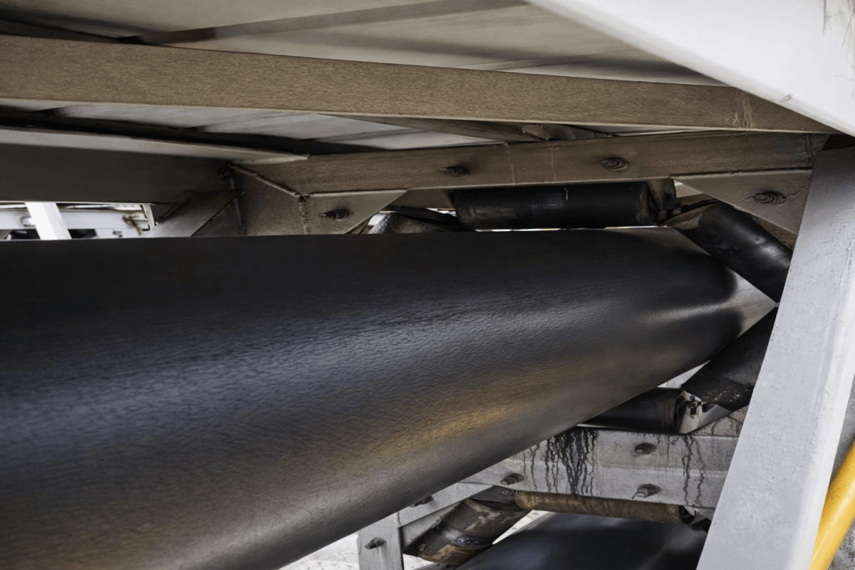 Pipe conveyor belt operating inside industrial conveying system for enclosed bulk material transport