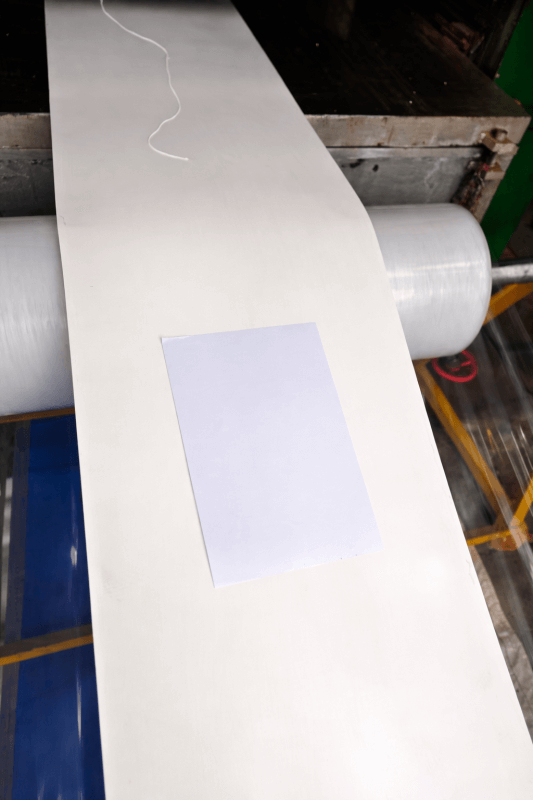 Smooth surface white conveyor belt in production line with paper sample for comparison